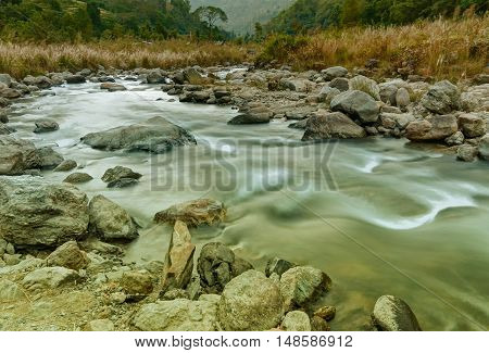 Beautiful Reshi River water flowing through stones and rocks at dawn Sikkim India. Tinted image. Reshi is one of the most famous rivers of Sikkim flowing through the state and serving water to many local people.