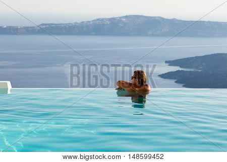 Man on the edge of an infinity pool watching the scenery