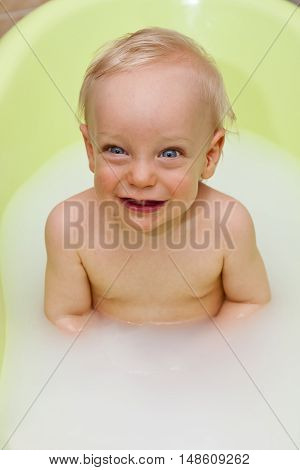 Happy baby having bath in milk water
