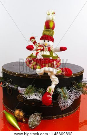 Funny snowman sits on vintage brown coffer with white christmas tree decoration copy space