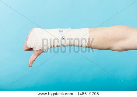 Bad news and information. Medicine aspects. Male hand with bandage showing thumb down sign symbol.