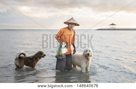 Bali Indonesia September 11th 2016: old fisherman with dogs