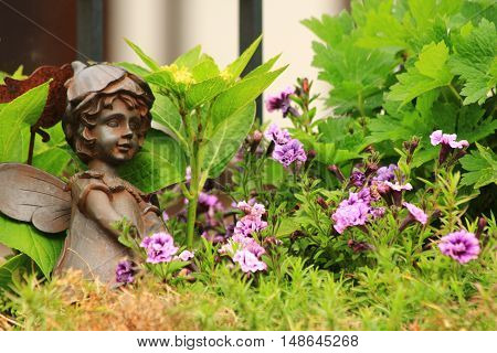 Flower-bed with an angel statue and green plants