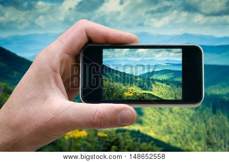 phone in hand man photographing the landscape photos from your phone, Selfie, photographing on the phone, the man photographs the mountain landscape on the phone smartphone side view. carpathians