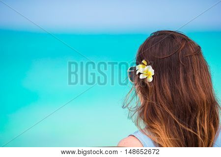 Young beautiful woman during tropical beach vacation. Enjoy suumer vacation alone on the beach at Africa with frangipani flowers in her hair