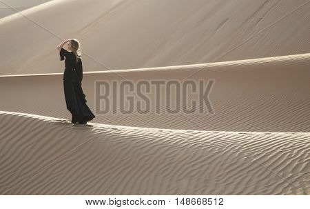 A woman in abaya in sanddunes in Liwa Desert Aby Dhabi UAE