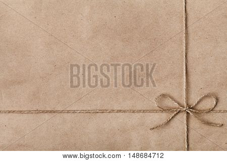 String or twine tied in a bow on kraft paper texture. New Year or Christmas gift or present concept.