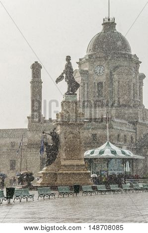 Quebec City, Canada - July 27, 2014: Crowd of people walking in heavy rain on boardwalk street with Champlain Monument statue on Dufferin Terrace