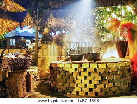 Riga Latvia - December 26 2015: People enjoy a hot traditional meal near the huge pot at Christmas market in Riga Latvia. It is the oldest market in Latvia. Motion blur. Selective focus.