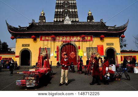 Pengzhou China - February 1 2014: Vendors selling Chinese New Year incense sticks in front of the Buddhist Long Xing Temple entry pavilion