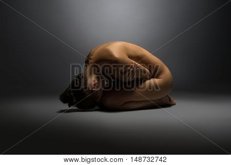 Concept of vulnerability. Naked woman lying on floor, hugging herself