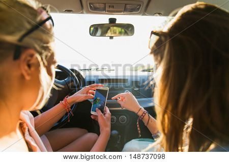 summer vacation, holidays, travel, road trip and people concept - happy teenage girls or young women with smartphone taking selfie in car