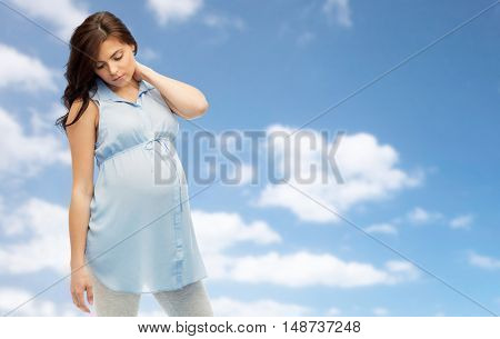 pregnancy, health, people and expectation concept - pregnant woman in bed touching her back and suffering from neckache over blue sky background