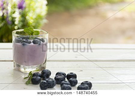 Yogurt Blue Berry and fresh berry on  wooden white table on background outdoor view.Close up.002