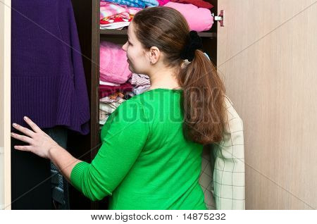 สาวคอเคซัสในตู้เสื้อผ้าชุดสิ่งบนมี Shelfs