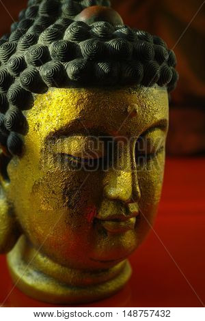 Gold Buddha face on dark red background