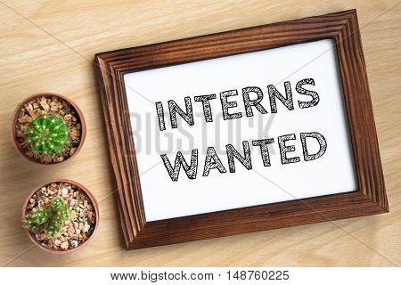 interns wanted, text message on wood frame board on wood table / business concept / Top view