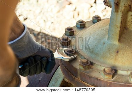 Hands with Work Gloves Holding a Wrench and Tighten very Rusty Bolts