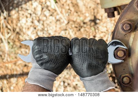 Hands with Work Gloves Holding a Wrench and Tighten very Rusty Bolts