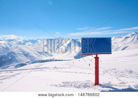 Bird view on the ski village in valley. Background of snowboard resort from the high peak. Winter season for advertising or billboard. Copy space on the sign.