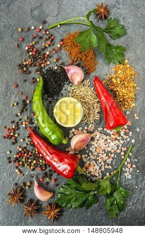 Pepper lime garlic parsley spices and salt are on the black stone . Top view