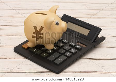 The yuan currency A golden piggy bank and calculator on a wood background with symbol of yuan symbol