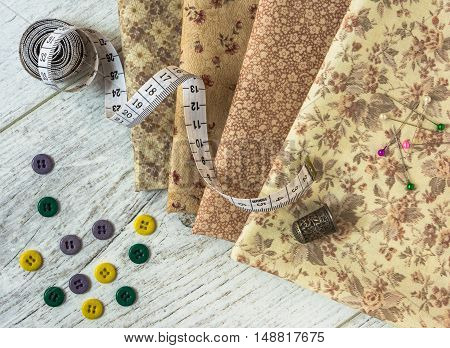 vintage cloth measuring tape thimble colorful buttons pins lie on a light wooden table. Top view