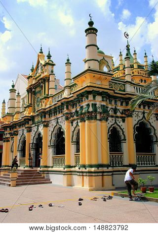 Singapore - December 18 2007: Man removing his shoes before entering the 1907 Masjid Abdul Gaffoor Mosque in Little India