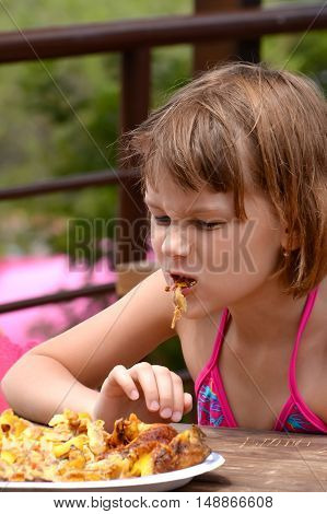 very hungry girl eats grilled chicken in the outdoor