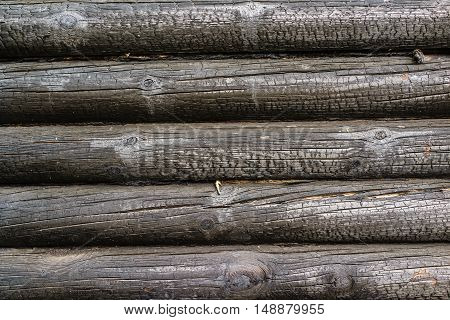 Charred wall of the house of pine trees logs. Burnt wall of the house. Conceptual background charred walls of the timber. Burnt pattern. Burnt wooden house wall. Black burned wooden house texture.