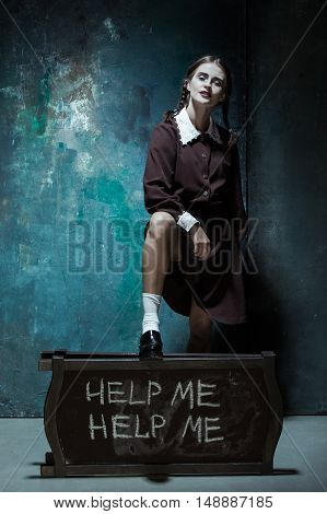 Halloween theme: Portrait of a young smiling girl in school uniform as killer woman against school board . The image in the style of Halloween and Addams family