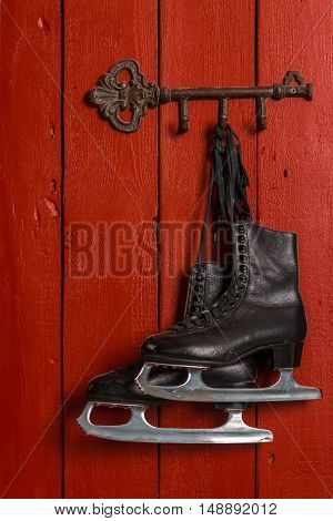 Old Black Figure Ice Skates Hanging On A Red Wooden Wall