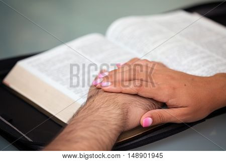 Couple with hands on a Holy Bible