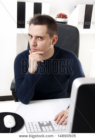 Mladý muž myšlení u počítače