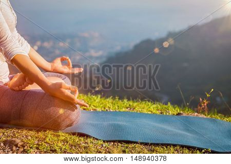 Close up of woman in Padmasana yoga lotus pose with chin mudra outdoors with copyspace. With light leak and lens flare