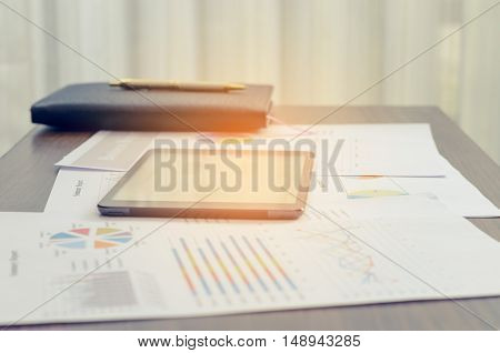 Tablet And Documents Chart On Wood Table Cartain Blackground