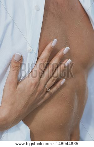 Sexy muscular naked man and female hands unbuckle his jeans.