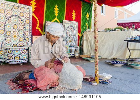 Badajoz Spain - September 23 2016: Sculptor arabic man working sculpting sculpture in market during celebration of Almossassa Badajoz Extremadura spain