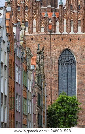 Mariacka Street With Colorful Facades Of Tenement Houses And 16Th Century Gothic St. Mary's Church, 