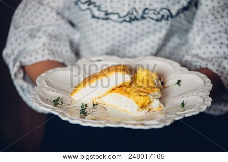 Women Holding A Plate With A Lush Omelet In French. Omelet With Cheese And Milk.