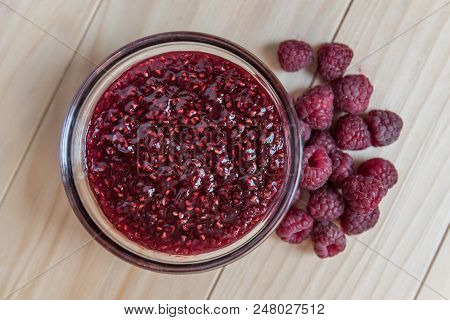 Homemade Raspberry Jam In A Glass Bowl With Fresh Ripe Organic Raspberries On A Wooden Table