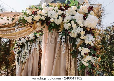 Magnificent Wedding Arch For A Wedding Ceremony. The Square Arch Decorated By Golden Fabric And Flow