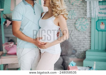 Crop Of Husband And Pretty Pragnant Woman Posing At Studio And Embracing Stomach. Fashionable And St