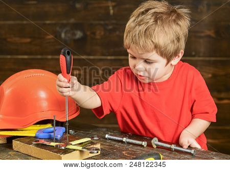 Blond Kid Playing In Workshop. Boy Binding Screws To Wooden Board. Concentrated Child Learning New S