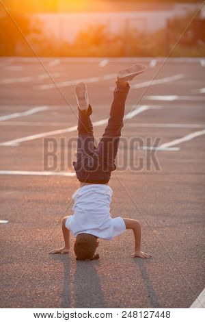The Boy Is Showing A Headstand On The Street