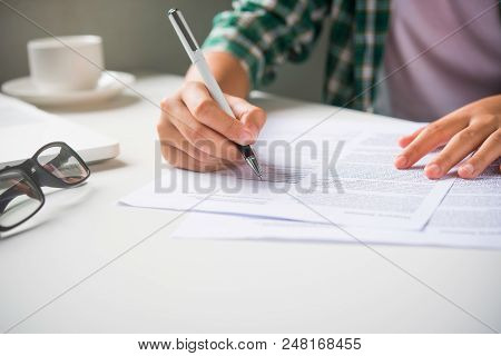 Close Up Of Woman Hands Writing Inon Paper Placed On Wooden In Office