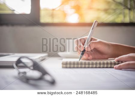 Close Up Of Woman Hands Writing Inon Paper Placed On Wooden In Office