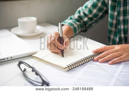 Close Up Of Woman Hands Writing Inon Paper Placed On Wooden In Office