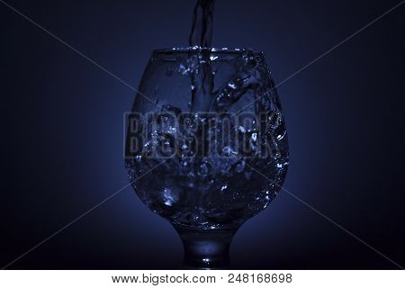 Simple Still-life Photo Of Whisky Glass, Water Jet And Dim Colour Light