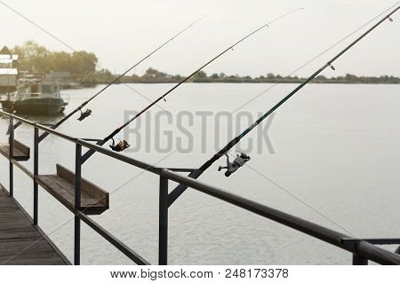 Three Fishing Rods With Reels, Spinning Stands In A Row On The Brackets, Catching Fish On The River,